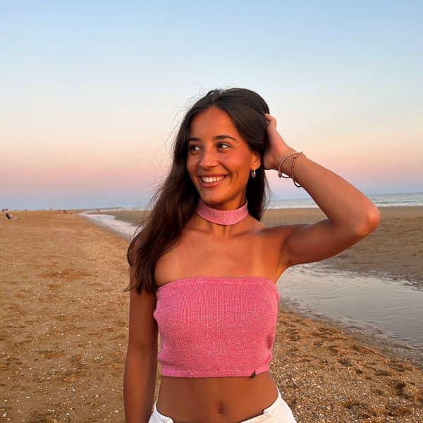 chica en la playa con una banda rosa con brillo plateado y choker del mismo tejido en el cuello