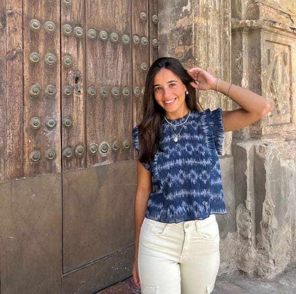 chica en la calle delante de una puerta rústica con bluda fruncida de color azul