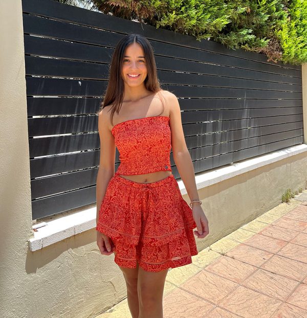 chica en la calle con un conjunto de top y falda de color coral