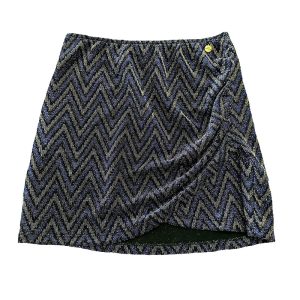 falda corta de tejido con hilo metalizado en tonos azul, cobre y negro haciendo dibujo de zigzag con cruce en frontal y fruncido en lateral izquierdo