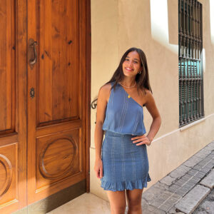 chica posando delante de una puerta con vestido asimétrico de color azul