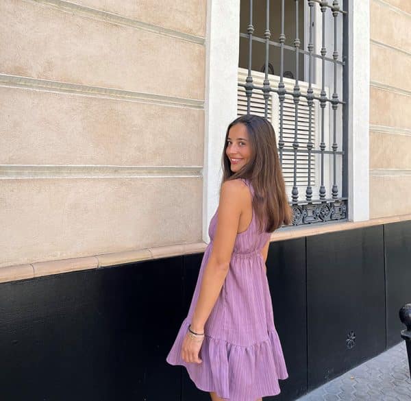 chica en la calle de espaldas con vestido playero rosa viejo